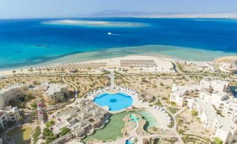 aerial view of a resort with a pool surrounded by water , sandy beaches , and palm trees at Kempinski Hotel Soma Bay