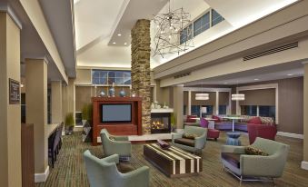 a modern hotel lobby with comfortable seating , a large fire pit , and a tv mounted on the wall at Residence Inn Waldorf