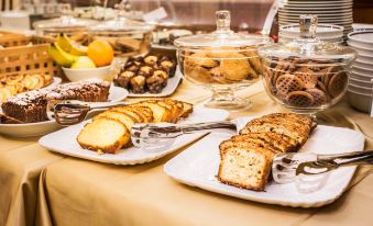 a table filled with various types of bread and pastries , along with fruit on display at Phi Hotel Principe