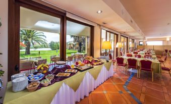 a dining room with a buffet table filled with various food items , including fruits , sandwiches , and desserts at Hotel Santa Gilla