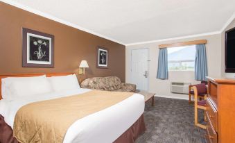 a hotel room with a bed , couch , and window , along with various items on the table at Grand Forks Inn