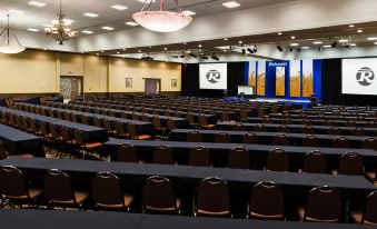 a large conference room with rows of chairs arranged in a semicircle , and a podium at the front at Bismarck Hotel and Conference Center