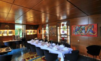 a long dining table is set with white plates and silverware in a room with wooden walls at Hotel-Restaurant Bären