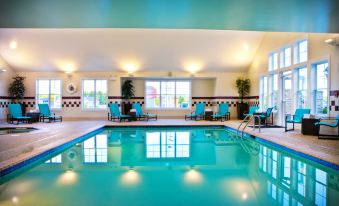 an indoor swimming pool with a blue and white color scheme , surrounded by chairs and tables at Residence Inn Auburn