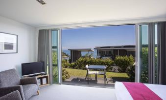 a bedroom with a large window and sliding glass door leading to an outdoor patio at Doubtless Bay Villas