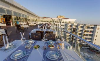 a rooftop dining area with tables set up for a meal , overlooking a city skyline at Senza Grand Santana Hotel