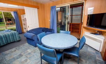 a dining room with a round table and blue chairs , next to a blue couch at Discovery Parks - Hadspen
