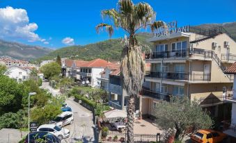 a street with buildings on both sides , a palm tree in the middle , and cars parked along the side at D&D Apartments