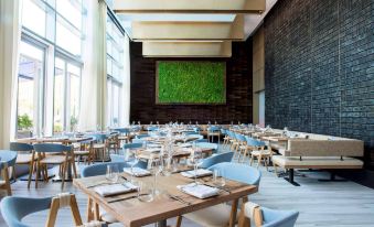 a large , modern restaurant with wooden tables and chairs , blue chairs , and a green wall at W Hoboken