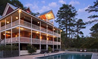 a large house with a pool and balcony is surrounded by trees at dusk , creating a serene atmosphere at Glen-Ella Springs Inn