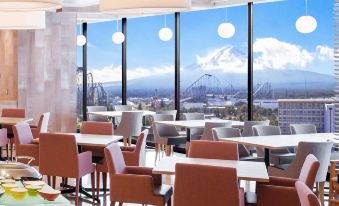 a restaurant with wooden tables and chairs , large windows , and a view of the city at HOTEL MYSTAYS Fuji Onsen Resort