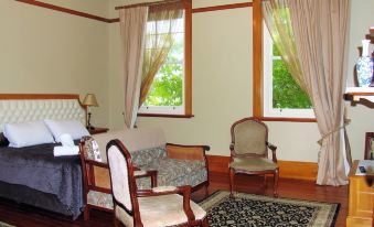 a room with wooden furniture , including chairs and a couch , situated in front of large windows at Left Bank