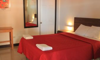 a bed with a red blanket and two white towels on it , in front of a mirror at Hotel Playa Bonita