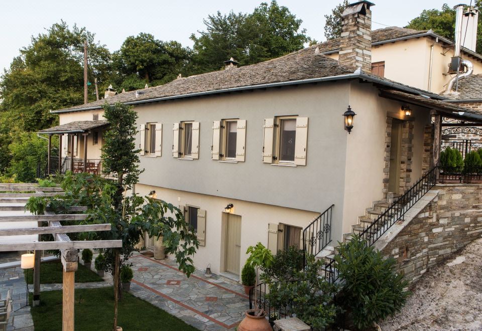a house with a stone roof and white walls is surrounded by greenery , including trees at Olga