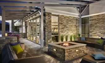 a modern outdoor living area with a stone fireplace , surrounded by comfortable seating and a dining table at SpringHill Suites Dallas Rockwall