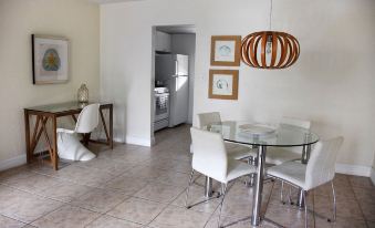 a dining room with a glass table and white chairs , next to a kitchen with an oven and refrigerator at Coral Reef at Key Biscayne