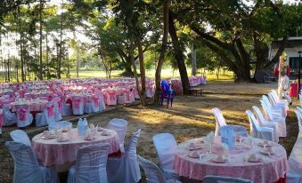 a large outdoor dining area with multiple tables covered in pink tablecloths and set for a special event at Tonnam Resort