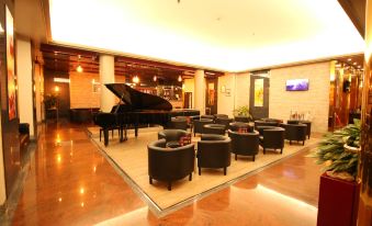 a modern , well - lit lobby with large wooden floors and multiple black furniture , including a grand piano at Hotel Diplomatic