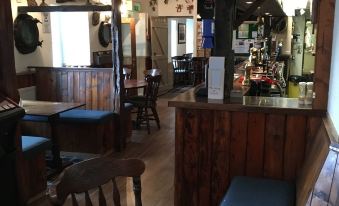 a restaurant with a bar and several chairs , including one that is covered in a blue tablecloth at Hartland Quay Hotel