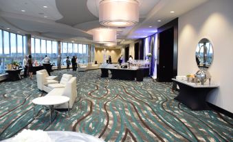 a large , modern hotel lobby with several people standing or sitting around tables and chairs at Holiday Inn Cincinnati N - West Chester