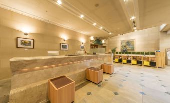 a modern hotel lobby with marble walls , wooden benches , and a reception desk , under the illumination of ceiling lights at Hotel JAL City Aomori