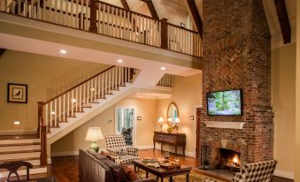 a cozy living room with a fireplace , a couch , a tv , and a staircase leading to the second floor at Barnsley Resort
