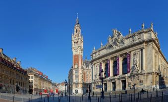 a grand , ornate building with a tall tower and red - tiled roof in the city square of lille , france at Holiday Inn LILLE - OUEST ENGLOS by IHG