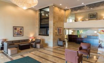 a large , modern hotel lobby with high ceilings , multiple seating areas , and a staircase leading to the second floor at Holiday Inn Hazlet