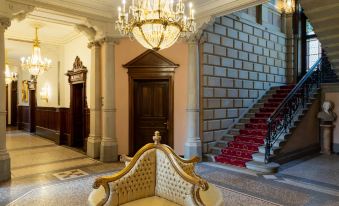 a grand hotel lobby with a chandelier hanging from the ceiling , a couch and stairs leading to the second floor at Schloss Lieser, Autograph Collection
