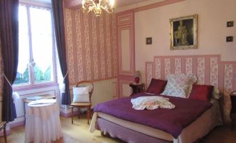 a pink and white bedroom with a large bed , a chair , and a chandelier hanging from the ceiling at Le Chateau