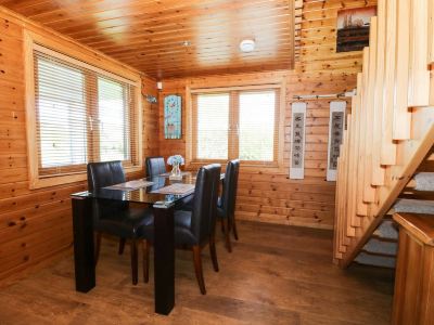 a dining room with a wooden table and chairs , surrounded by windows that allow natural light to fill the space at Moon Face