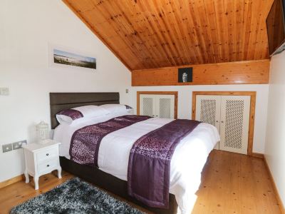 a large bed with a purple blanket is in a room with wooden walls and ceiling at Moon Face
