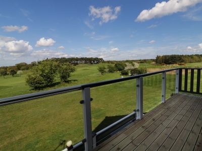 a balcony with a railing overlooking a green field and trees , under a blue sky with clouds at Moon Face