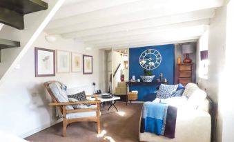 a cozy living room with a blue couch , a chair , and a clock on the wall at Garden View