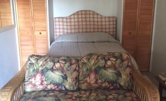 a bed with a floral comforter and wooden headboard is shown in a bedroom with white walls at Hillside Apartments