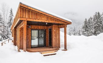 a wooden cabin is covered in snow , with a porch and door leading to the interior at Boulder Mountain Resort