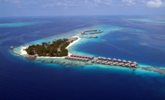 a tropical island with a few buildings on it and the ocean in the background at Coco Bodu Hithi