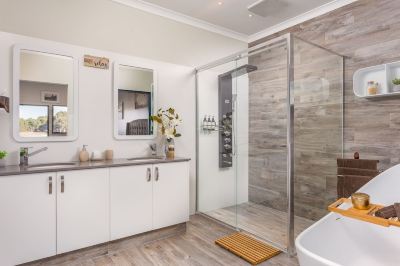 a modern bathroom with a glass shower enclosure , wooden flooring , and white furniture , including a sink and mirror at The Swan Valley Retreat