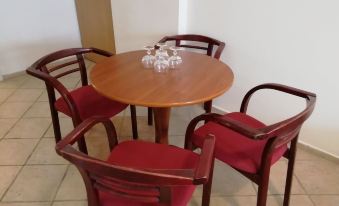 a wooden dining table surrounded by four red chairs in a room with white walls at Hotel 28
