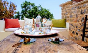 a wooden dining table with two cups and saucers placed on it , along with a potted plant in the background at Villa Rosa