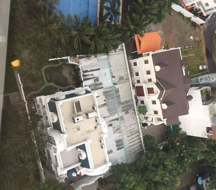 An aerial view reveals houses and gardens in a residential neighborhood featuring spacious swimming pools at La Casa We Stay