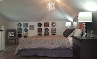 a cozy bedroom with a large bed , a chandelier hanging from the ceiling , and various musical albums on the walls at Devils Lake Inn