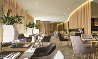 a modern dining room with multiple tables and chairs , creating a pleasant atmosphere for guests at Novotel Paris Nord Expo Aulnay
