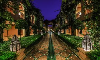 a beautiful courtyard with green plants , white lights , and a long walkway illuminated by night lights at Tikida Golf Palace