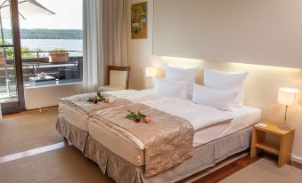 a large bed with a gold and white color scheme is situated in a room with a window at Seehotel Leoni