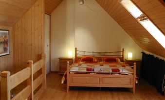 a wooden attic bedroom with a large bed , two nightstands , and a window overlooking the outdoors at Simcha