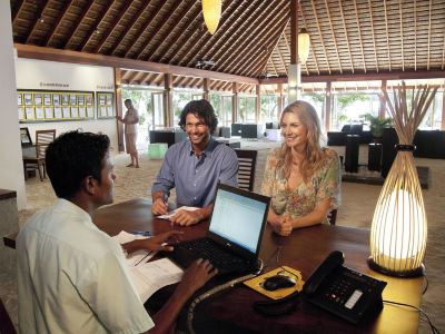 a group of people , including a man and a woman , are gathered around a desk in a restaurant at Vilamendhoo Island Resort & Spa