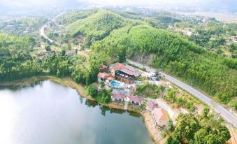 a bird 's eye view of a resort with a lake , surrounded by mountains and trees at Phong Nha Lake House Resort