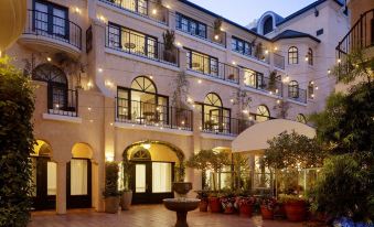 a hotel courtyard with a fountain in the center , surrounded by buildings and trees , lit up at night at El Prado