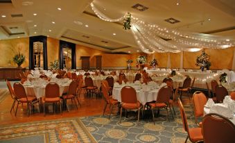 a large banquet hall with multiple tables set up for a formal event , surrounded by chairs and decorated with string lights at Best Western Parkway Inn  Conference Centre